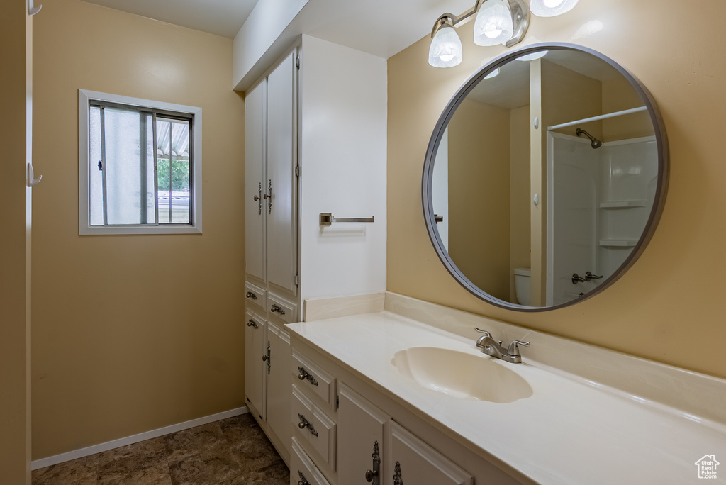Full bath with vanity, toilet, baseboards, and a shower
