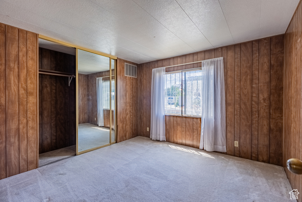 Unfurnished bedroom featuring carpet flooring, a closet, and wooden walls