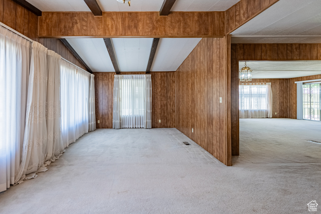 Carpeted spare room with a chandelier and wooden walls
