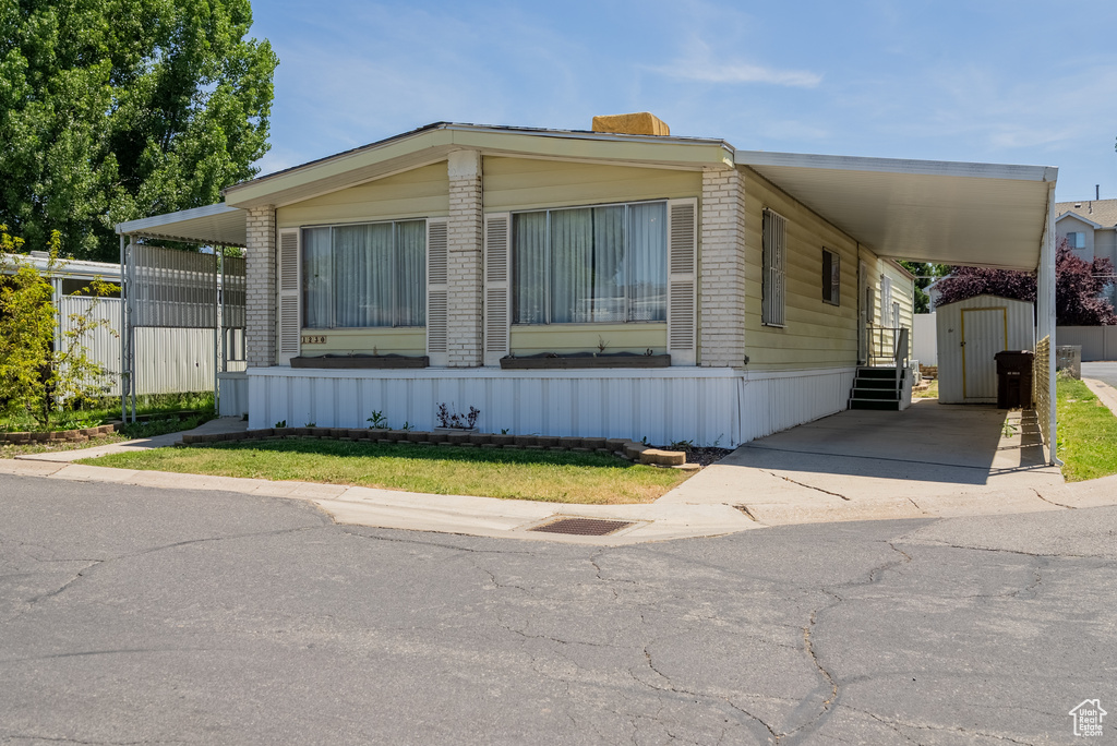 Manufactured / mobile home featuring a carport, brick siding, and driveway