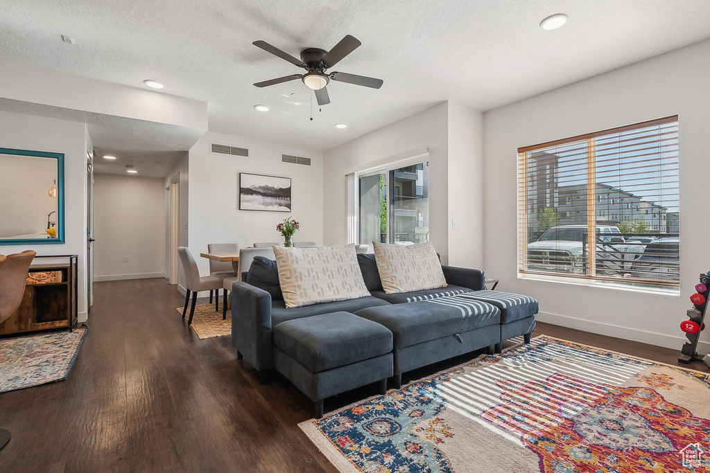 Living room with plenty of natural light, dark wood-style floors, baseboards, a ceiling fan, and recessed lighting