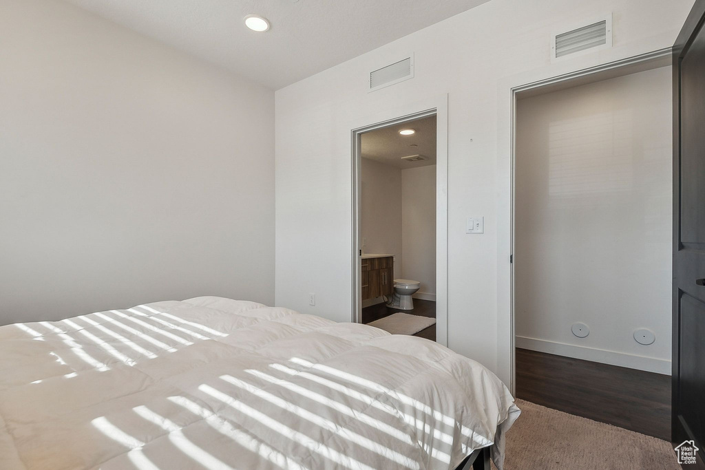 Bedroom featuring recessed lighting, baseboards, dark carpet, and ensuite bath