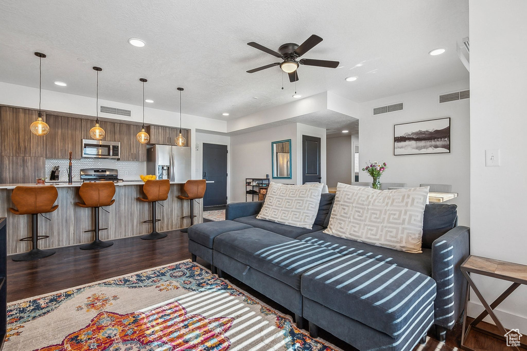 Living room with wood finished floors, ceiling fan, recessed lighting, and baseboards