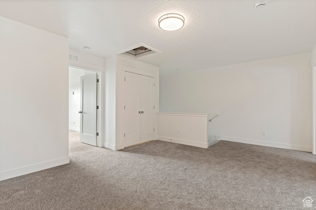 Carpeted spare room featuring a smoke detector, baseboards, and a textured ceiling
