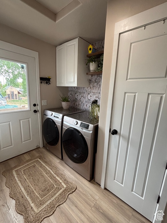 Washroom with washer and clothes dryer, cabinet space, and light wood-style flooring