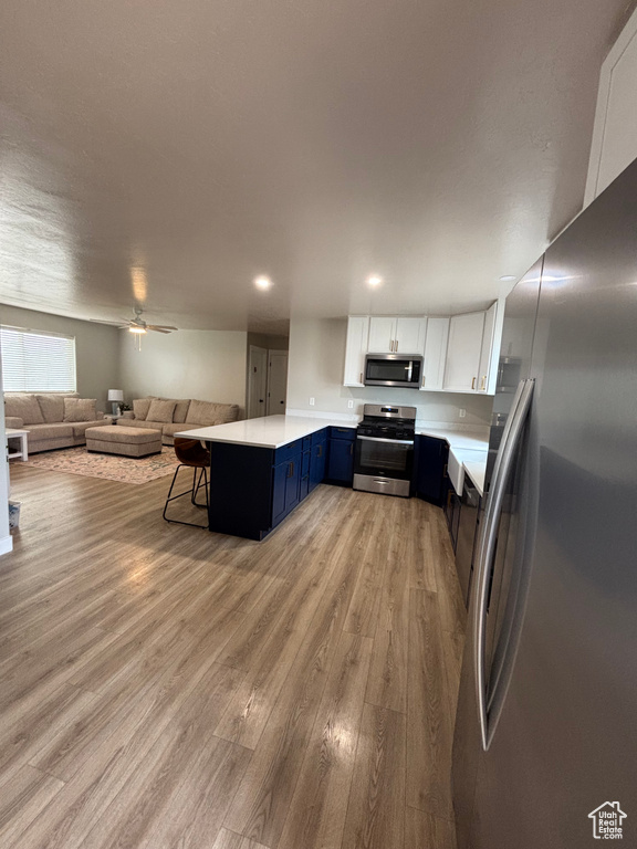 Kitchen with appliances with stainless steel finishes, a peninsula, open floor plan, and light countertops