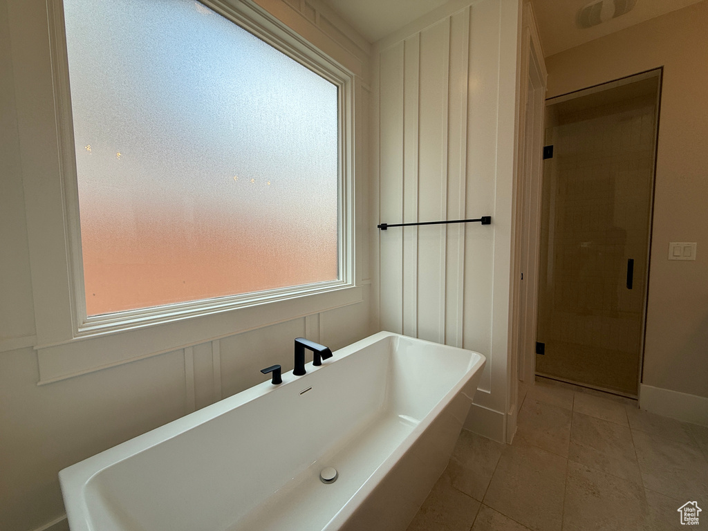 Bathroom featuring tile patterned flooring, a freestanding tub, a shower stall, and a sink