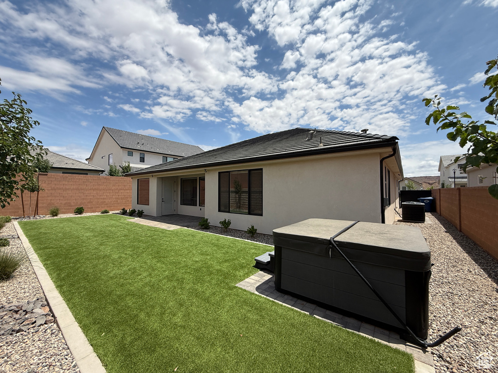 Back of house featuring a hot tub, stucco siding, and a tiled roof