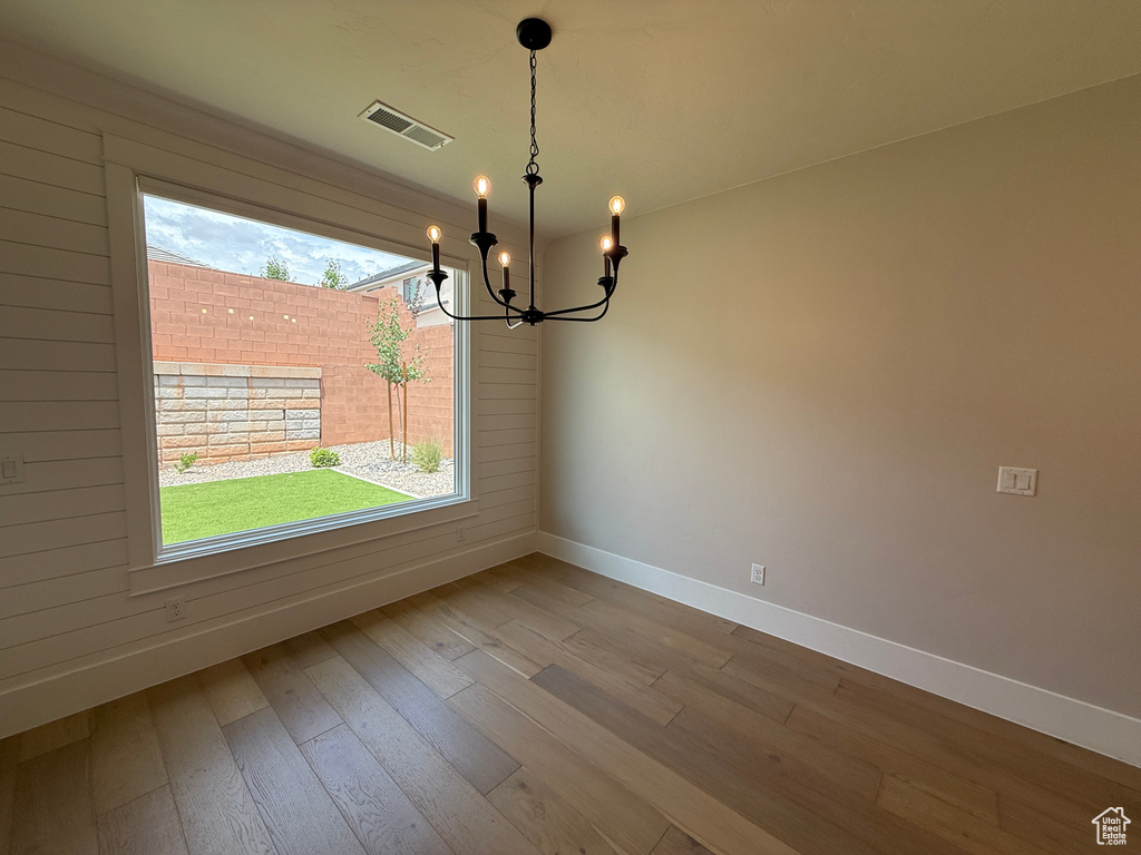 Spare room featuring baseboards, a chandelier, and wood-type flooring