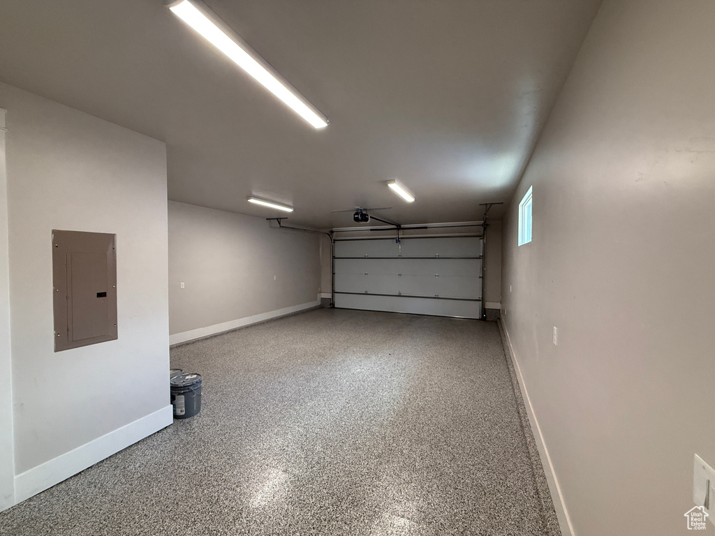 Garage with electric panel, baseboards, and a garage door opener