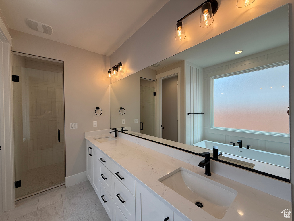 Bathroom with double vanity, a shower stall, baseboards, and tile patterned flooring