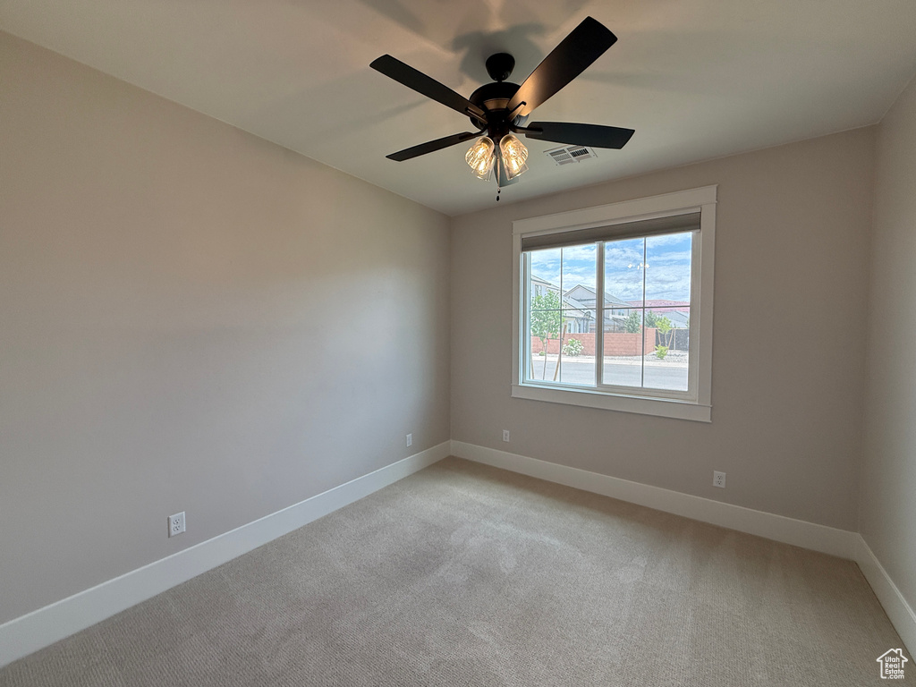 Unfurnished room featuring baseboards, light colored carpet, and a ceiling fan
