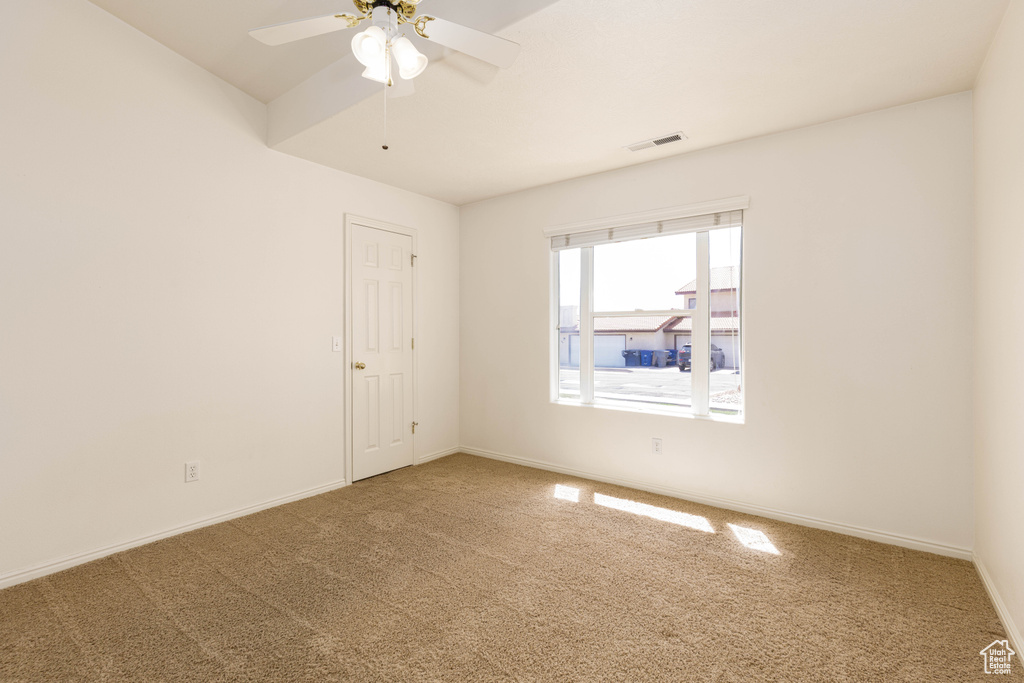 Carpeted spare room with ceiling fan and baseboards