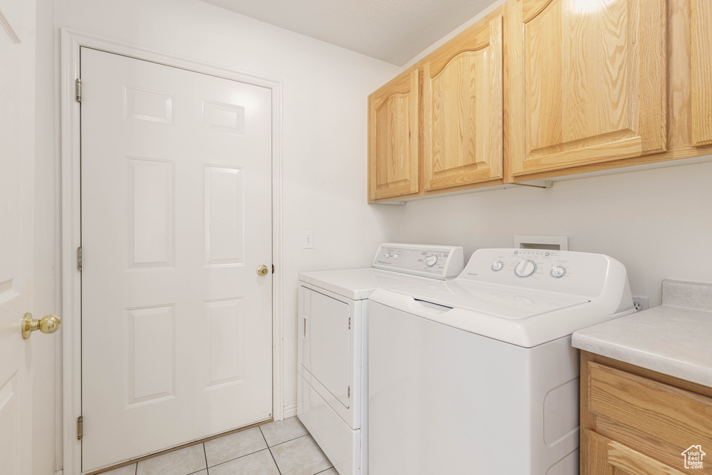 Laundry room with cabinet space, washer and dryer, and light tile patterned flooring