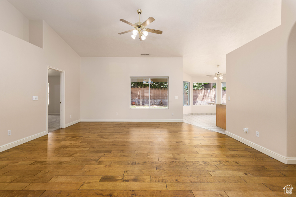 Unfurnished living room with a ceiling fan, wood-type flooring, arched walkways, and baseboards