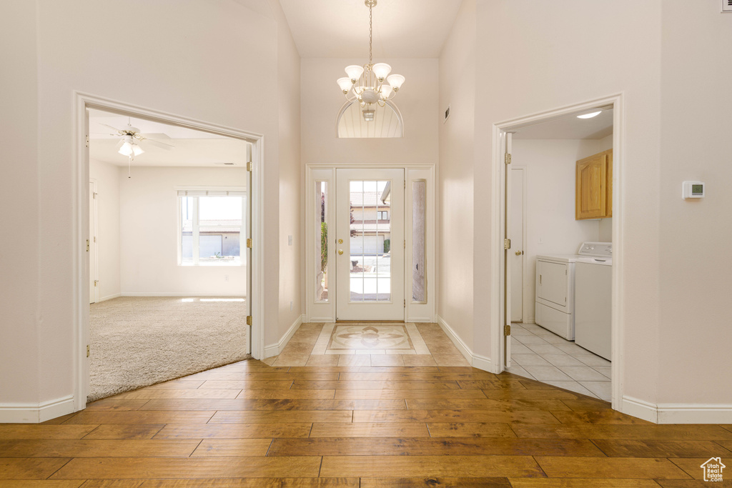 Entrance foyer with light wood-type flooring, washer and clothes dryer, a chandelier, a high ceiling, and baseboards