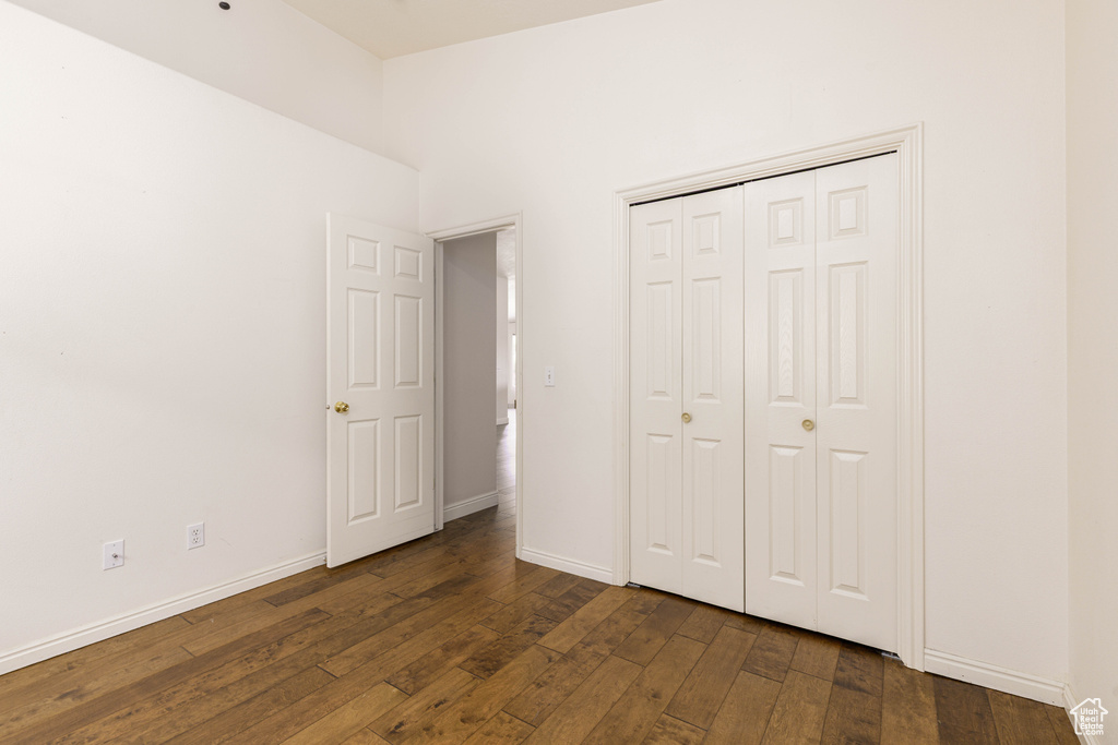 Unfurnished bedroom with hardwood / wood-style flooring, baseboards, and a closet
