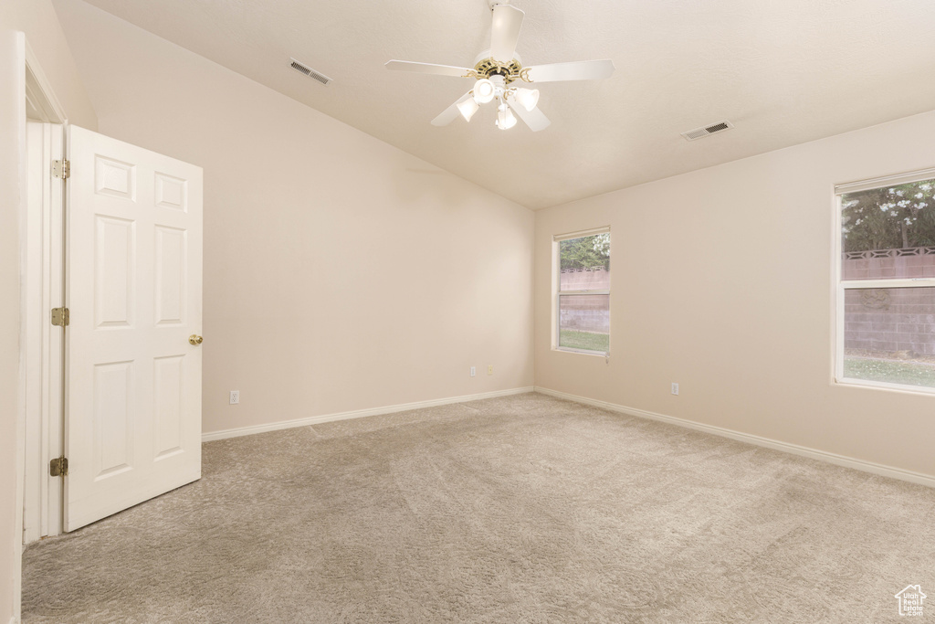 Empty room featuring vaulted ceiling, carpet floors, a ceiling fan, and baseboards
