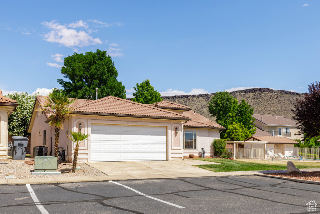 Mediterranean / spanish house featuring stucco siding, a tiled roof, a garage, central air condition unit, and concrete driveway