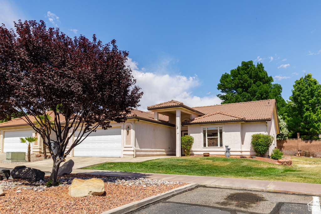 Mediterranean / spanish home featuring a tiled roof, a garage, stucco siding, and driveway