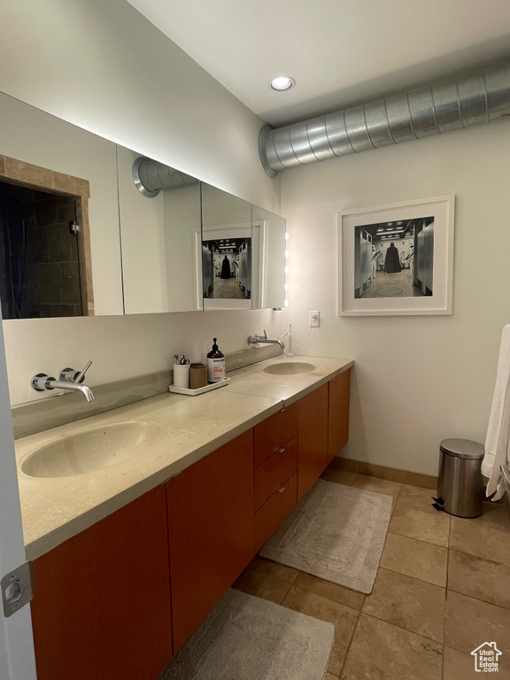 Full bath with double vanity, tile patterned floors, and baseboards