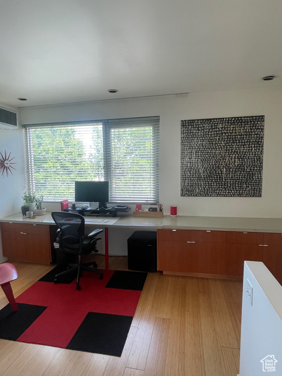 Office with light wood-style floors, built in study area, and healthy amount of natural light