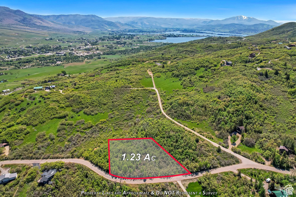 Aerial view of property and surrounding area with a water and mountain view and property parcel outlined