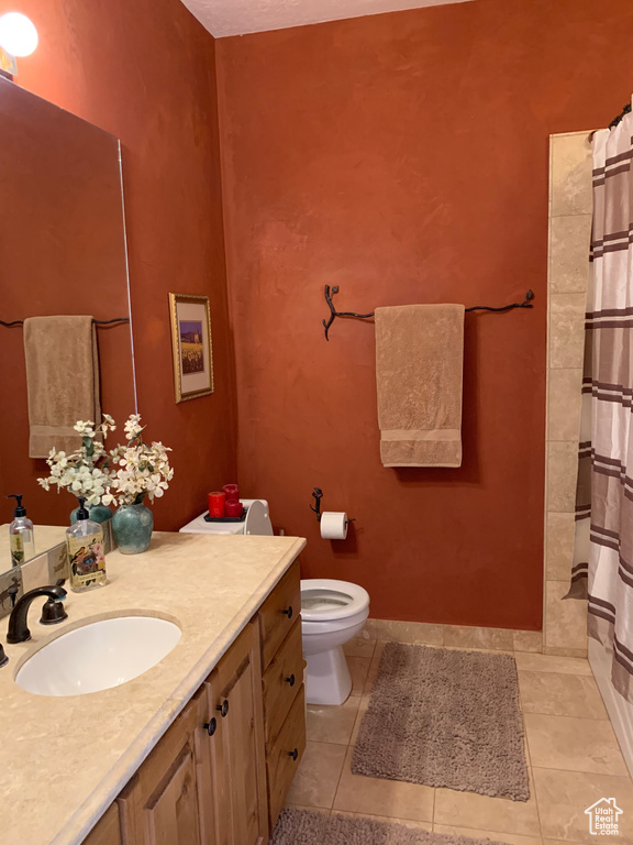 Full bathroom with vanity, toilet, tile patterned floors, and a shower with shower curtain