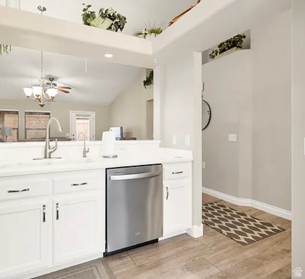 Kitchen with dishwasher, a sink, white cabinetry, light wood finished floors, and a chandelier