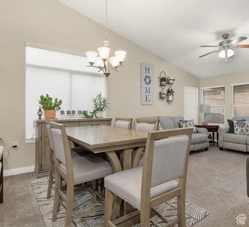 Dining area with light carpet, vaulted ceiling, a chandelier, ceiling fan, and baseboards