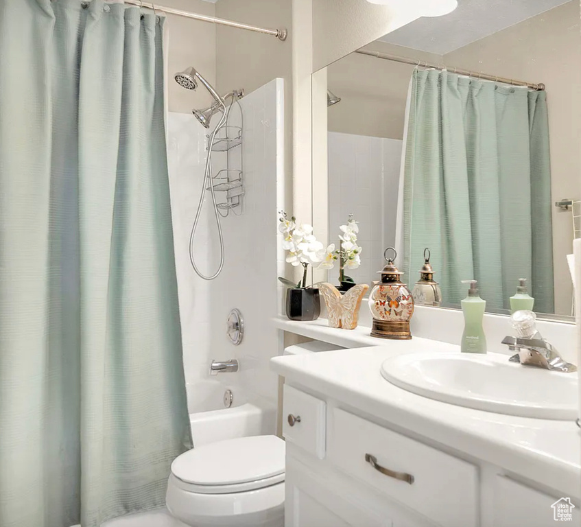 Bathroom with vanity, shower / bath combo, and toilet