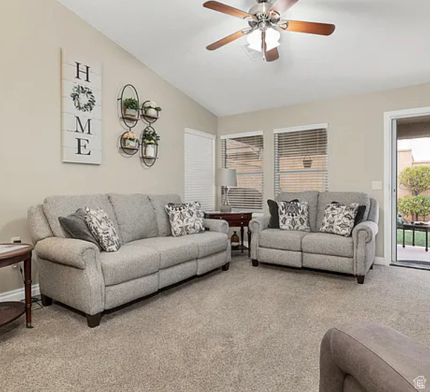 Living area with light colored carpet, ceiling fan, lofted ceiling, and baseboards