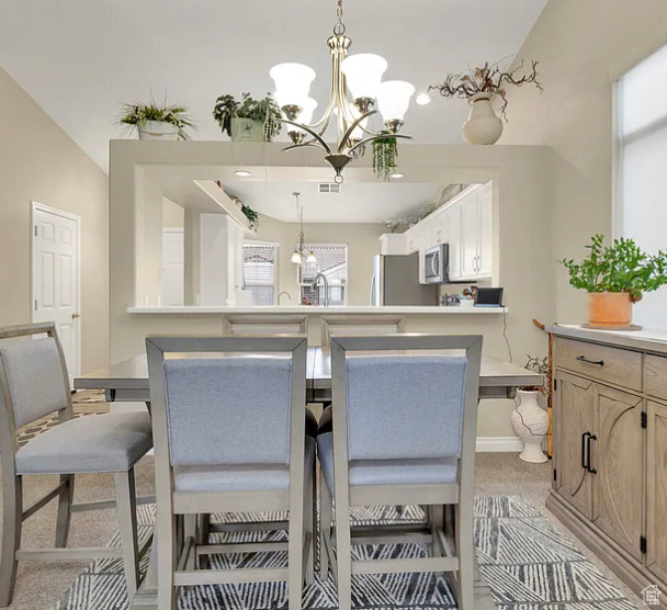 Dining room featuring a chandelier, light colored carpet, and baseboards