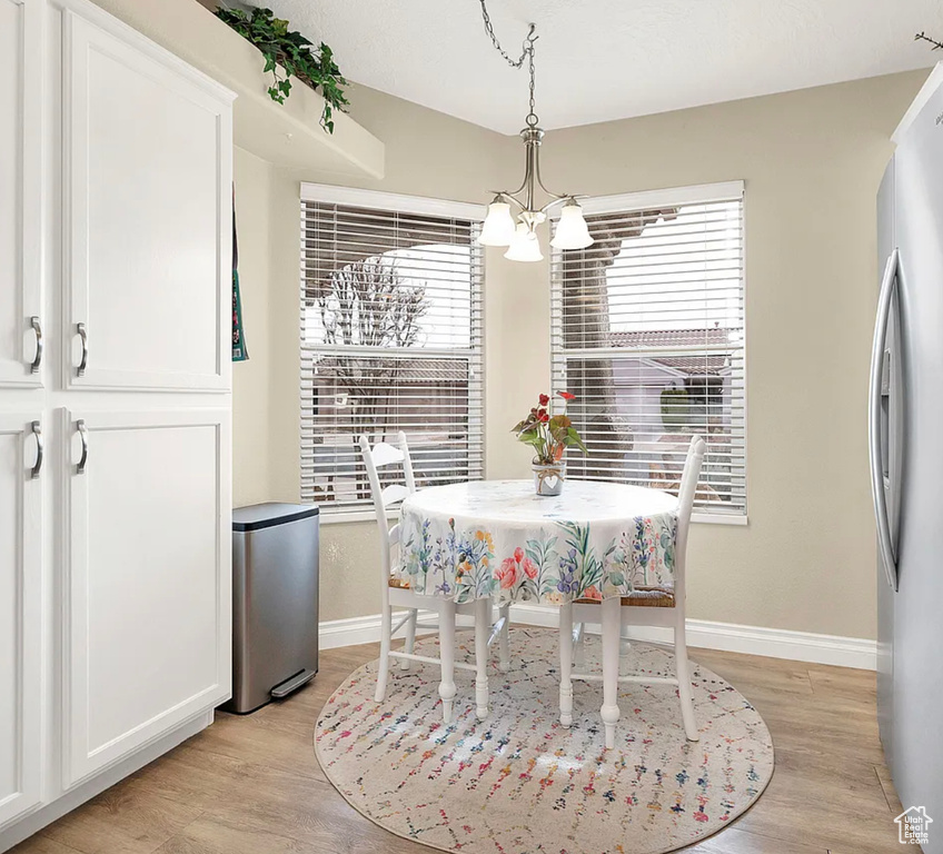 Dining space with a chandelier, light wood-style floors, and baseboards