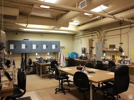 Office featuring light colored carpet, a workshop area, and electric panel