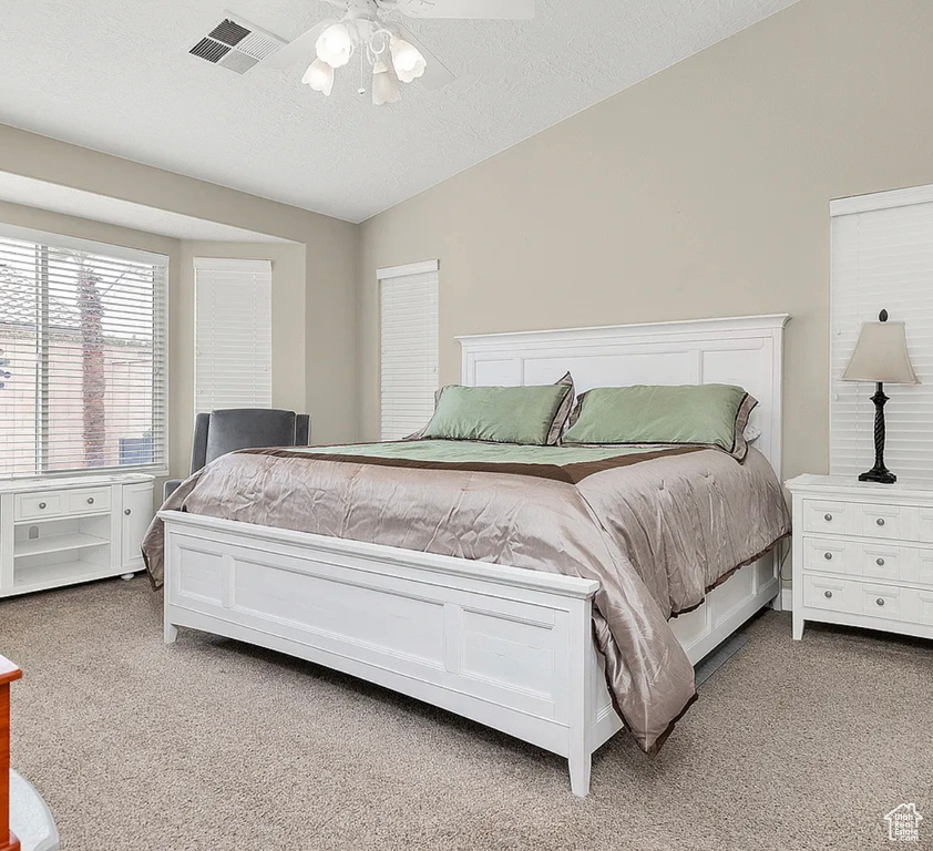 Bedroom with light carpet, vaulted ceiling, and a ceiling fan