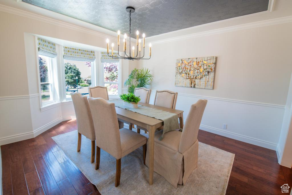 Dining area featuring a chandelier, hardwood / wood-style flooring, crown molding, and baseboards