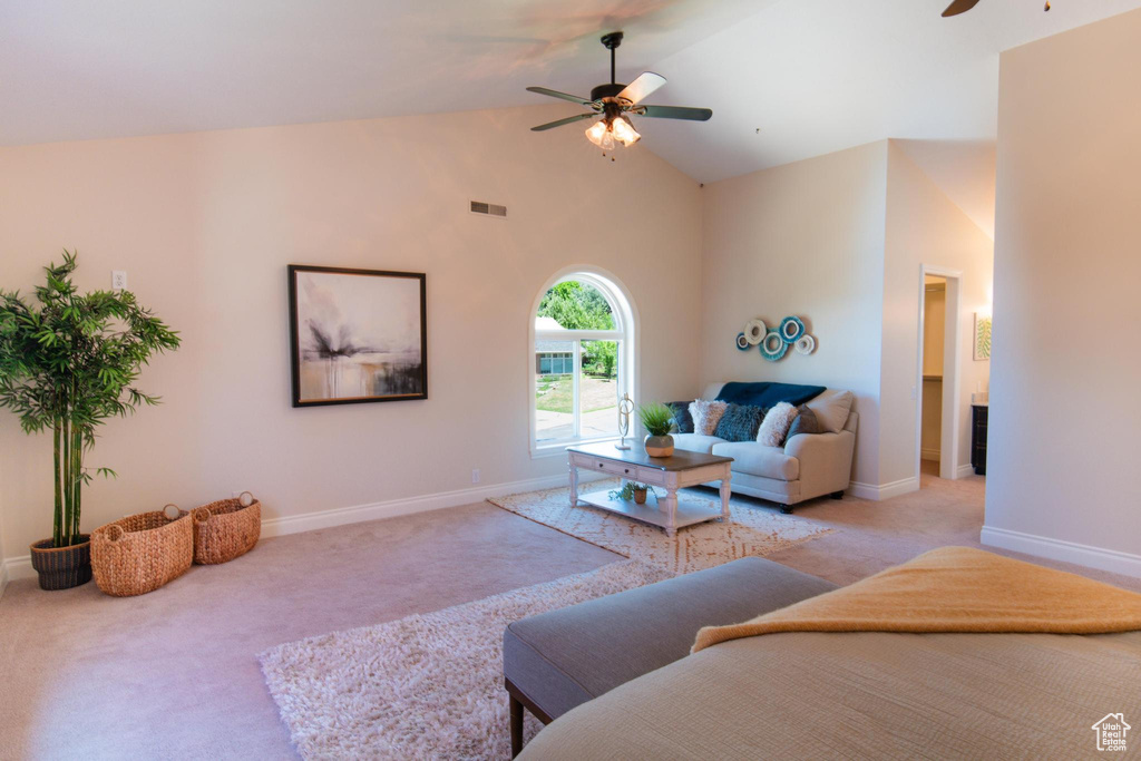 Living area with ceiling fan, light carpet, baseboards, and high vaulted ceiling