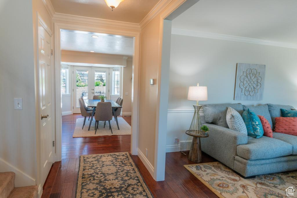 Living room featuring wood-type flooring, crown molding, and baseboards