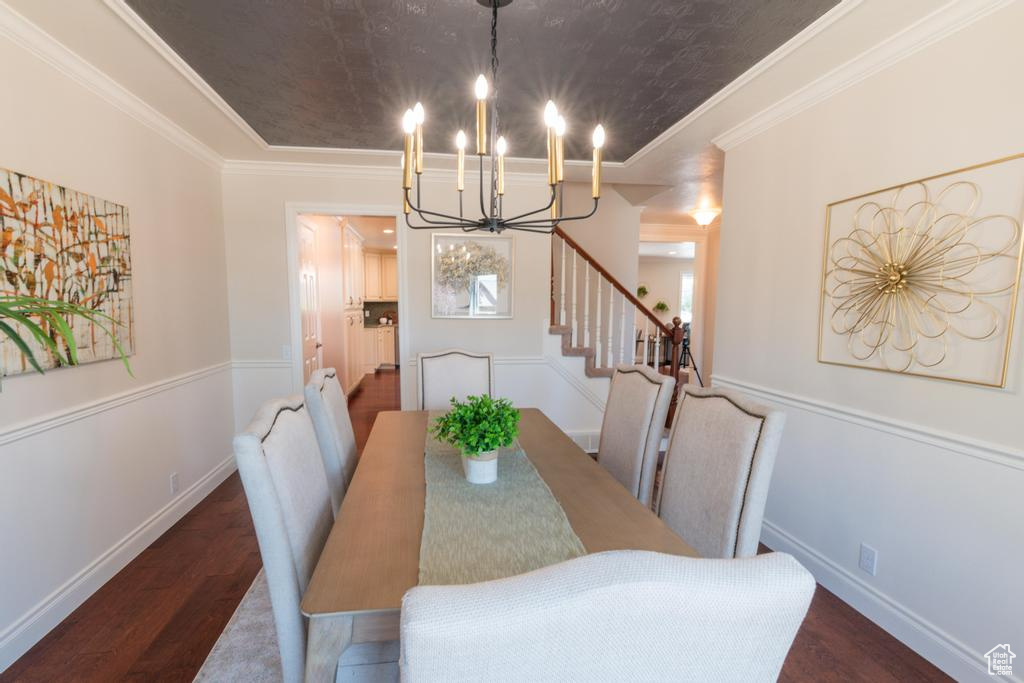 Dining room featuring a chandelier, wood finished floors, stairs, crown molding, and baseboards