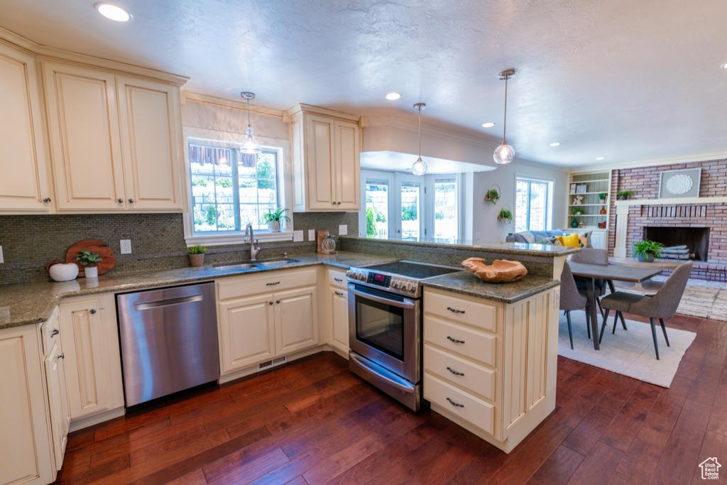 Kitchen featuring stainless steel appliances, a sink, a peninsula, dark wood-style floors, and recessed lighting