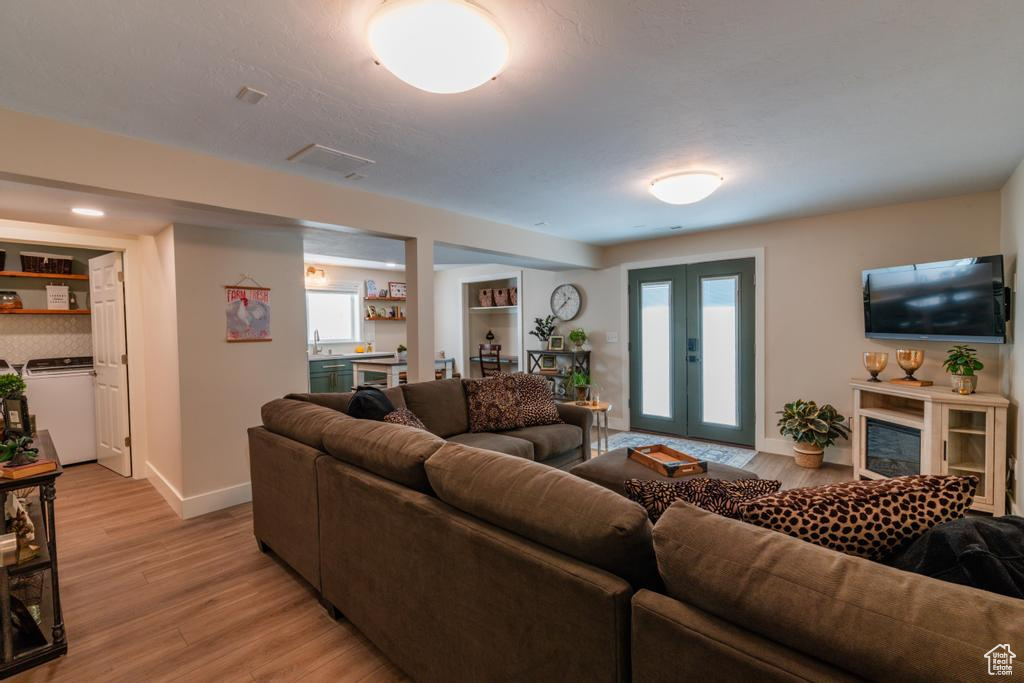 Living room featuring washer / dryer, light wood finished floors, and baseboards