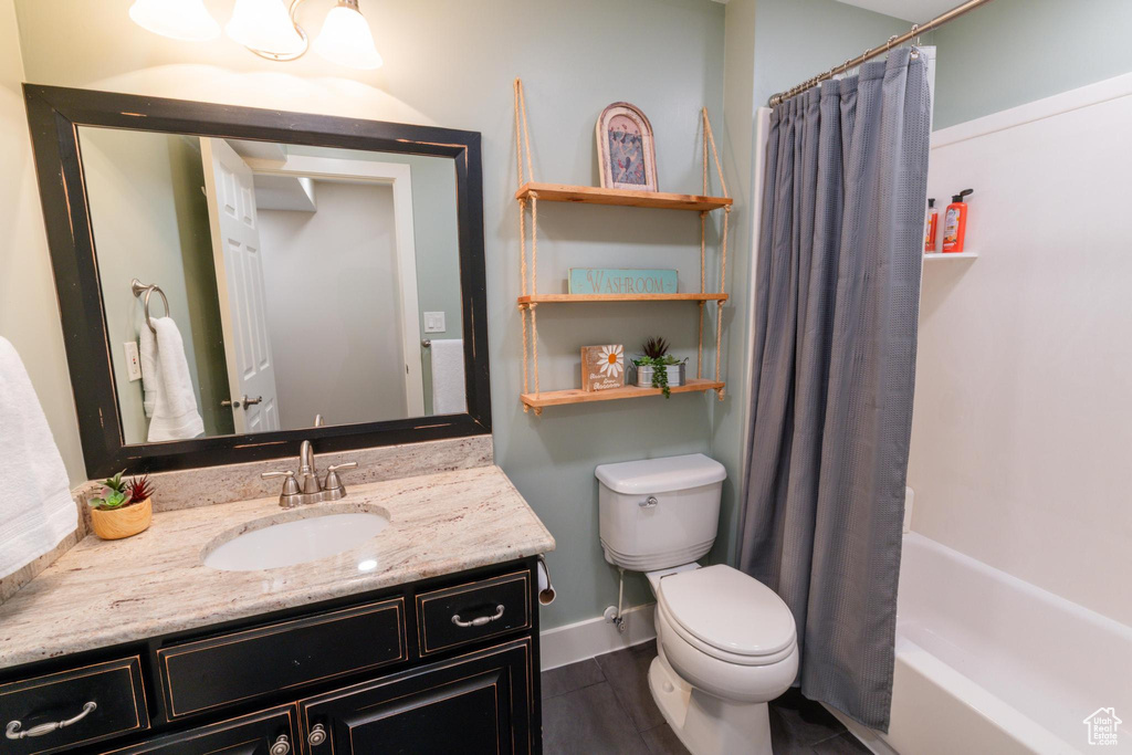 Full bathroom featuring vanity, toilet, shower / tub combo with curtain, and baseboards