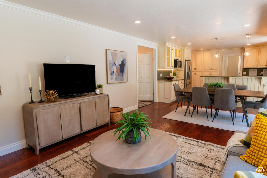 Living room featuring baseboards, dark wood-type flooring, ornamental molding, and recessed lighting