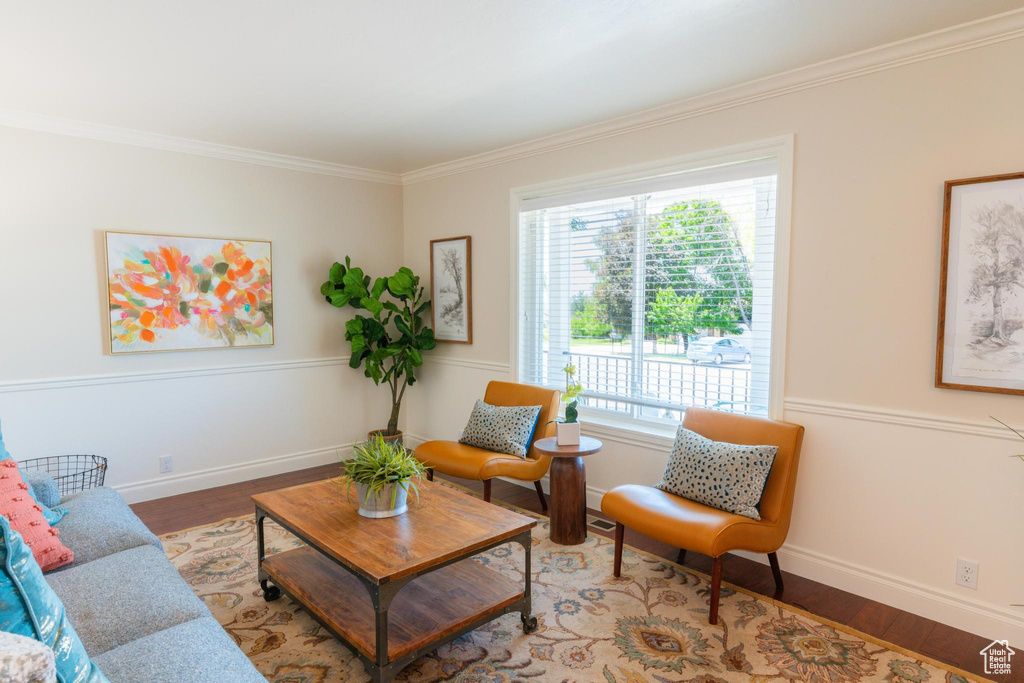 Living room featuring wood finished floors, crown molding, and baseboards