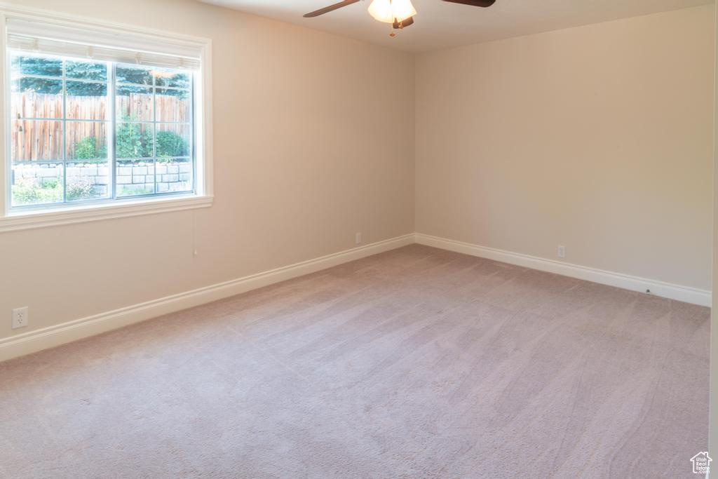 Empty room with a ceiling fan, light carpet, and baseboards