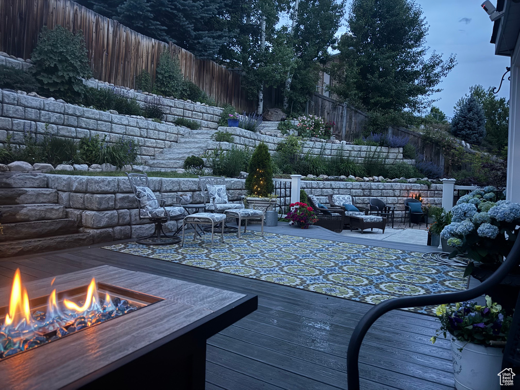 Wooden terrace with a fenced backyard and an outdoor living space with a fire pit