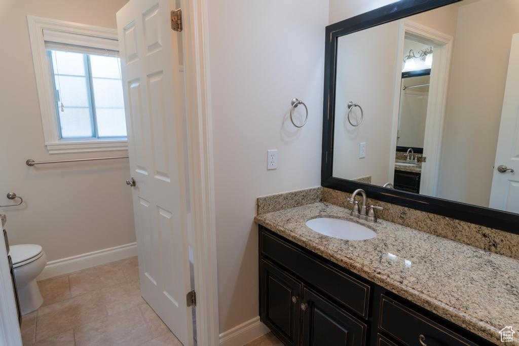 Bathroom featuring vanity, toilet, tile patterned flooring, and baseboards