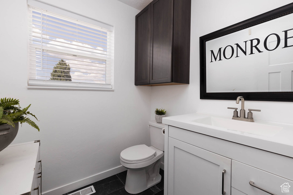 Half bath featuring vanity, toilet, baseboards, and tile patterned flooring