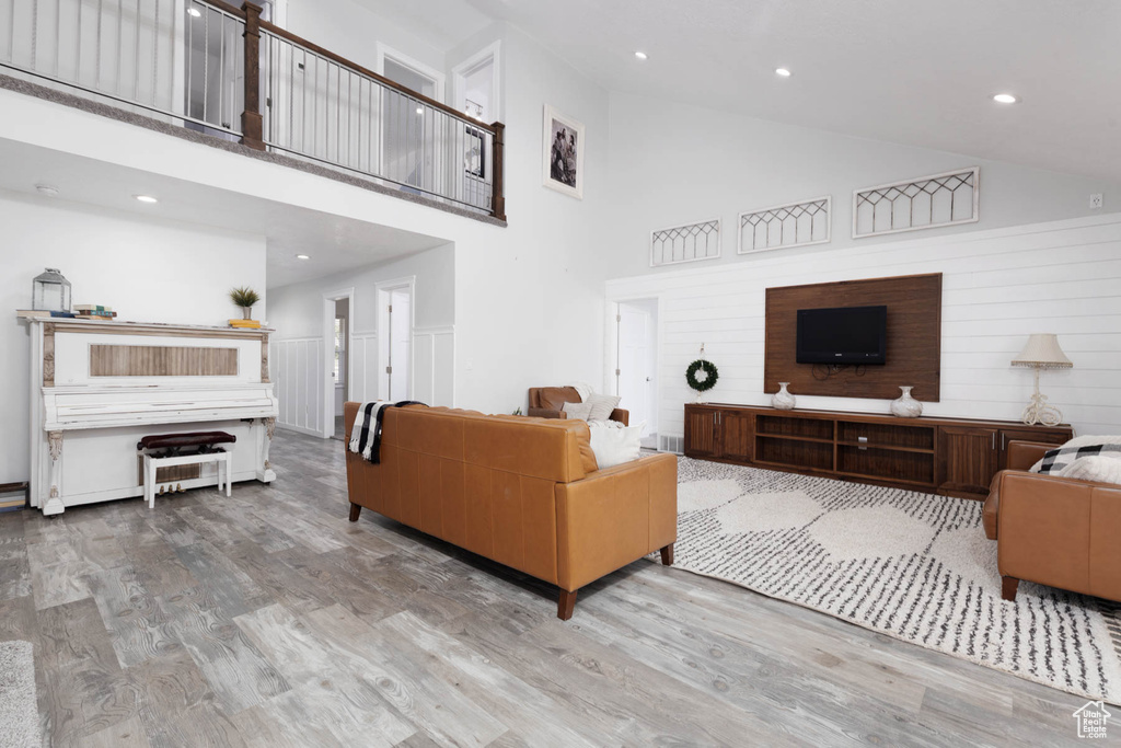 Living area featuring high vaulted ceiling, wood finished floors, and recessed lighting